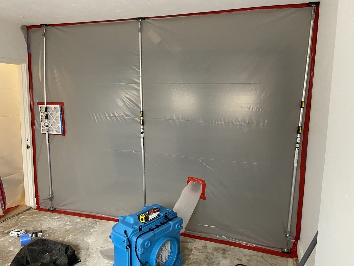 Sealed containment barrier with a negative air machine running for mold remediation