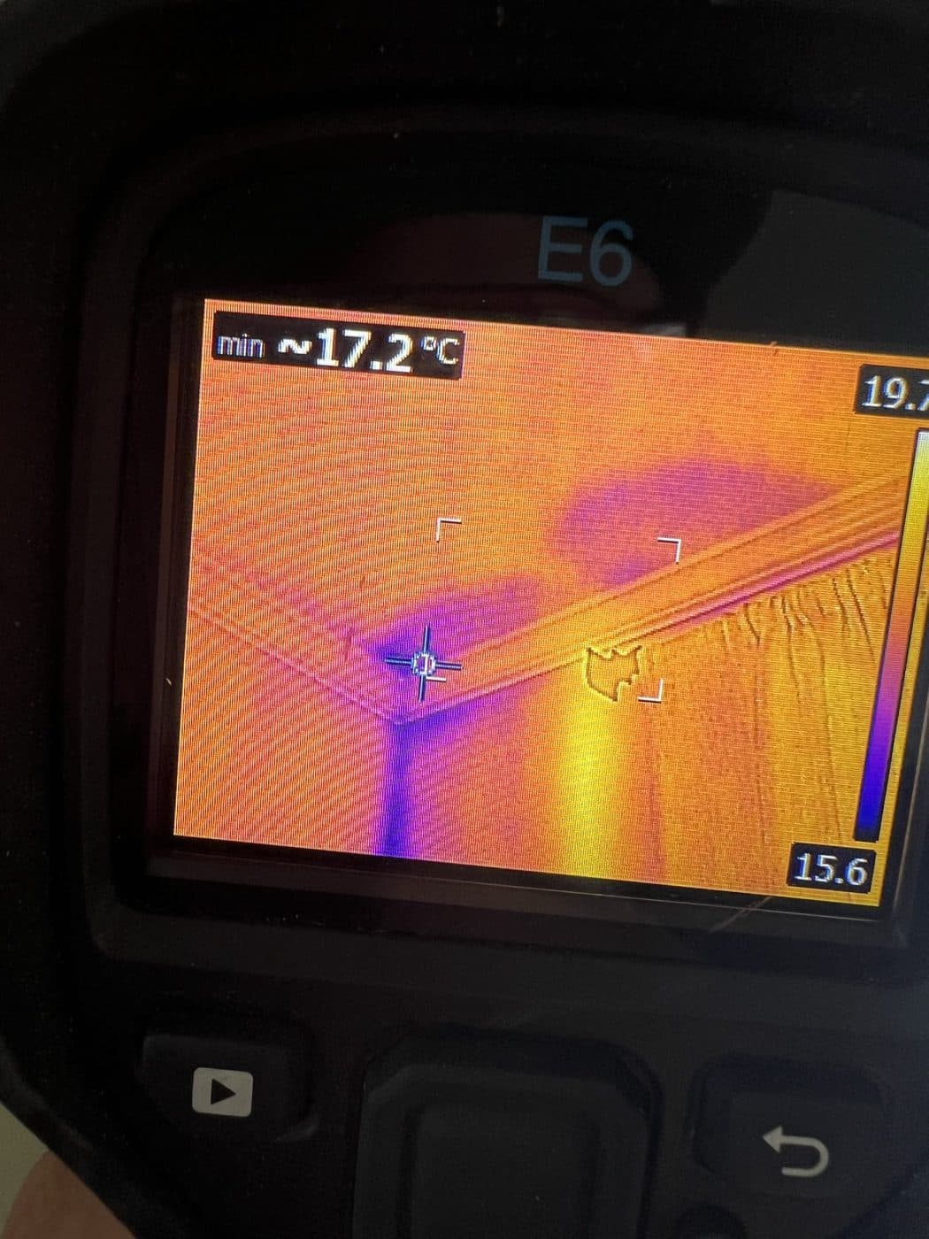 Close-up of a thermal imaging camera screen showing a moisture pattern behind a wall