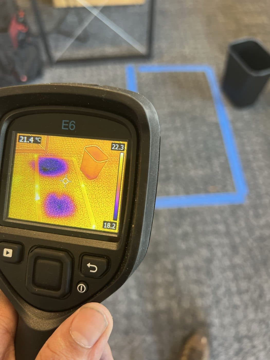 Technician using a thermal imaging camera to inspect for hidden moisture in carpet